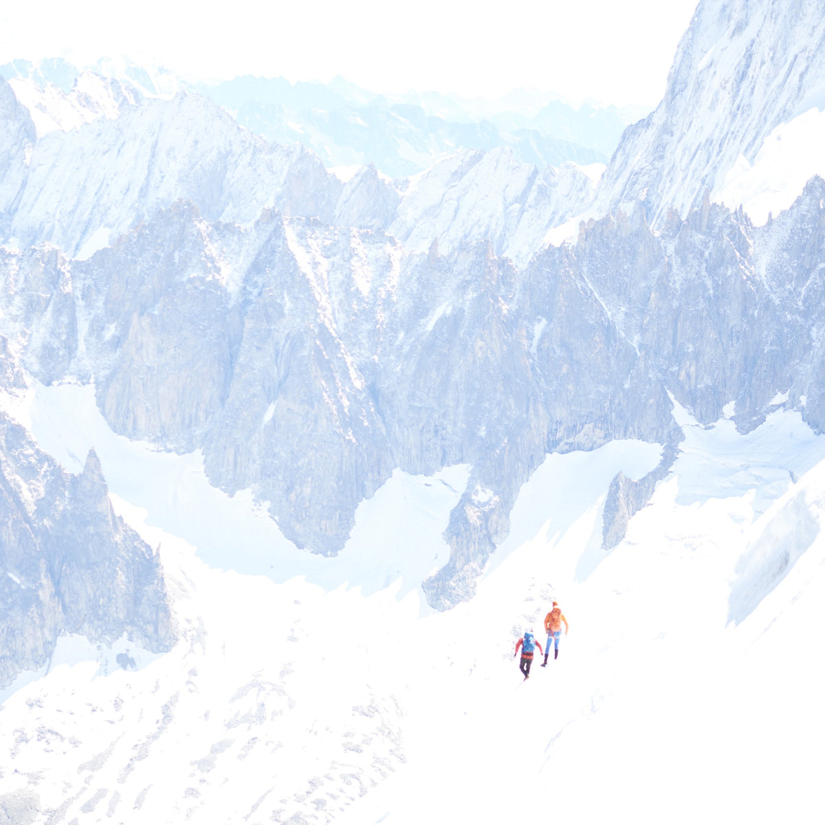 Two climbers crossing a snowfield below the peaks, France